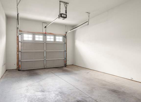 A large, empty garage with a metal gate and a lift.