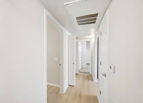 A long hallway with white walls and wood flooring.
