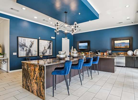 A kitchen with a blue accent wall and a marble island.