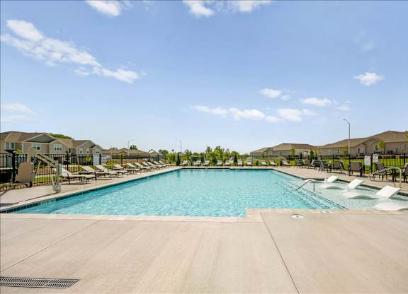 A large swimming pool with lounge chairs and a clear blue sky.
