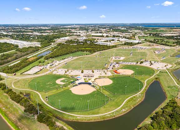 A large green field with a baseball diamond and a basketball court.