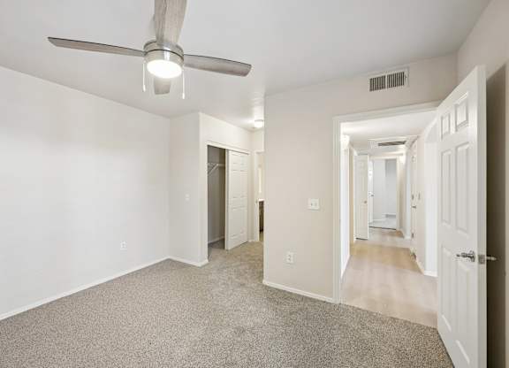 A room with a ceiling fan and carpeted floor.