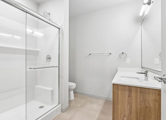 A white bathroom with a walk in shower and a sink.