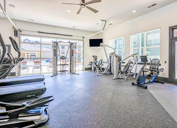 A gym with treadmills, exercise bikes, and a television.