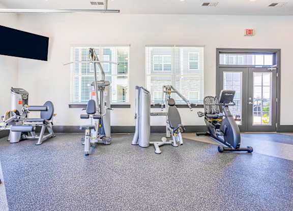 A gym with a variety of exercise equipment including treadmills, stationary bikes, and elliptical machines.