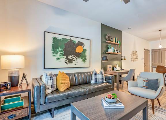 A living room with a grey couch and a painting on the wall.
