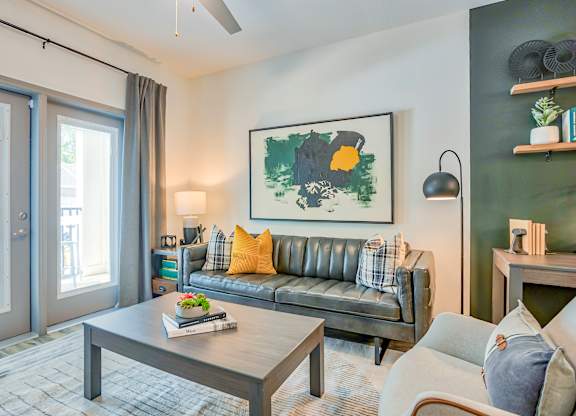 A living room with a grey sofa, a coffee table, and a painting on the wall.