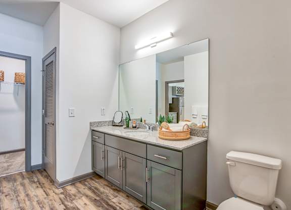 A bathroom with a toilet, sink, and mirror.