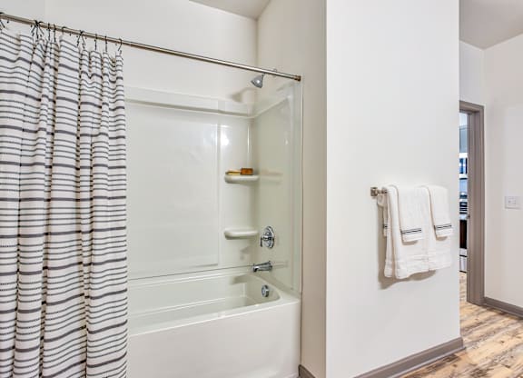 A white bathroom with a glass shower door and a white bathtub.