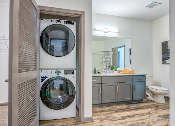 A white washer and dryer are stacked in a small laundry room.