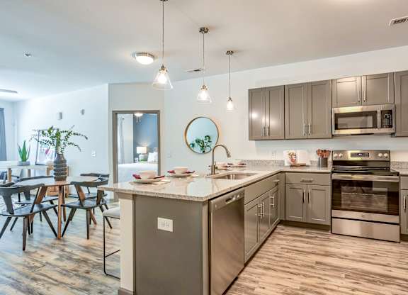 A modern kitchen with stainless steel appliances and wooden flooring.