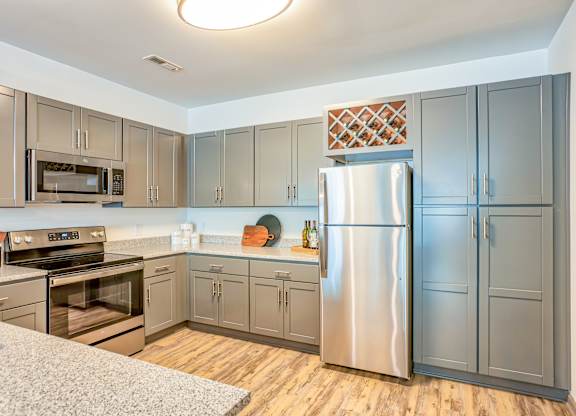 A kitchen with a refrigerator, oven, and microwave.