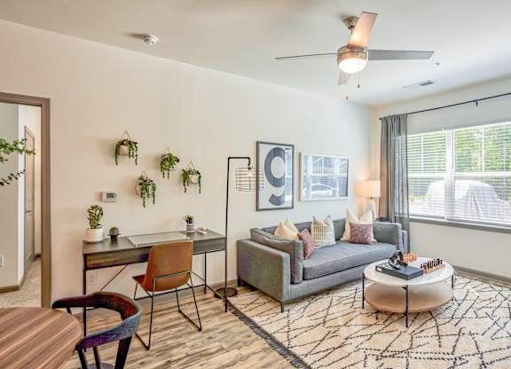 A living room with a grey couch, a coffee table, and a ceiling fan.
