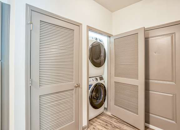 A washing machine is in a doorway between two rooms.