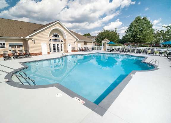 A large outdoor swimming pool with a slide and a building in the background.