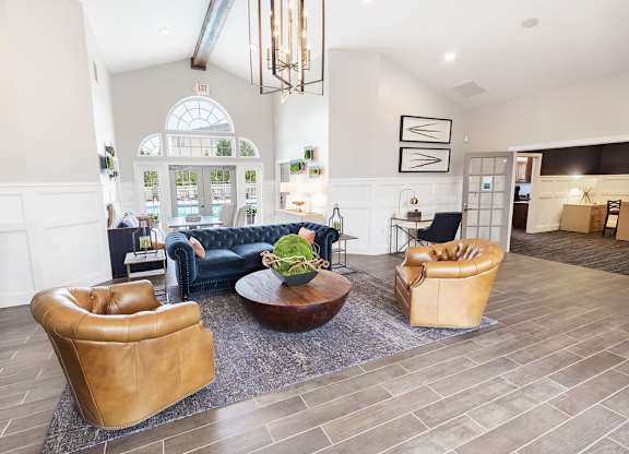 A living room with a blue couch, a brown leather chair, and a brown leather ottoman.