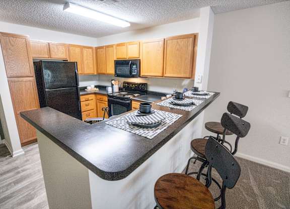 A kitchen with a black refrigerator, stove, and microwave.