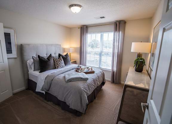 A bedroom with a large bed and a window with curtains.