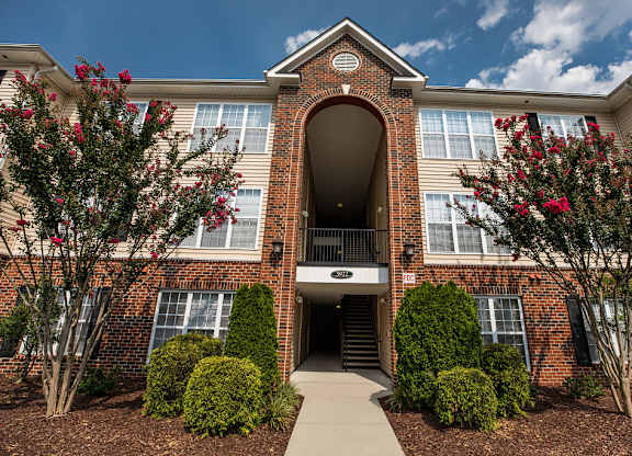 A red brick building with a large arched entrance and a walkway leading to it.