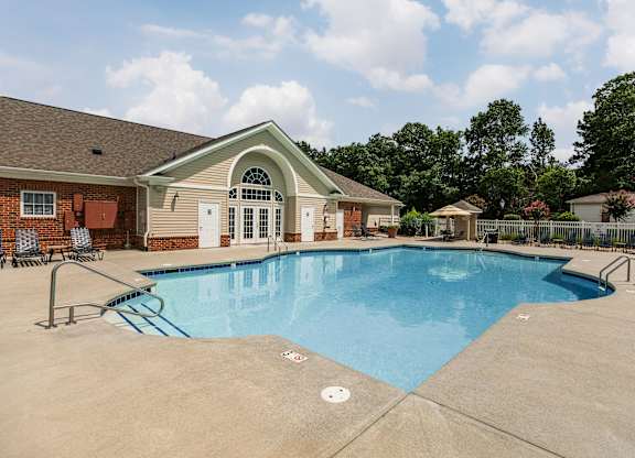 A pool in front of a house with a red awning.