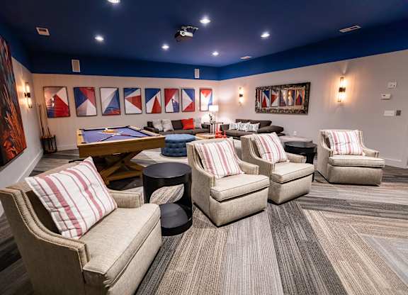 A room with a pool table and several chairs.