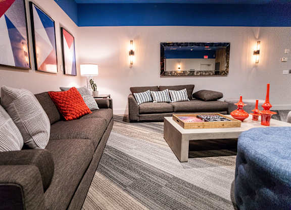 A living room with a grey couch, a coffee table, and a painting on the wall.