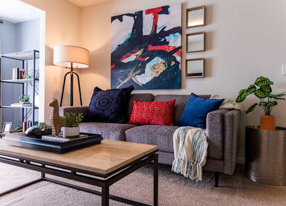 A living room with a grey couch, a coffee table, and a painting on the wall.