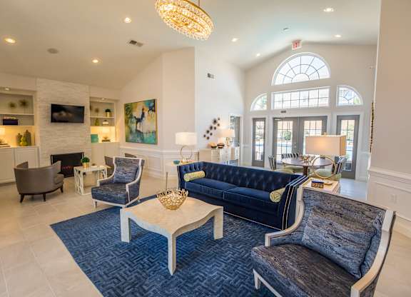A large room with a blue rug and a black couch.