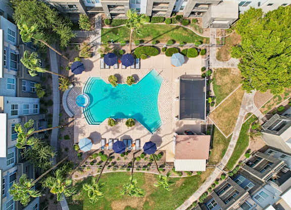 An aerial view of a swimming pool surrounded by buildings and trees.
