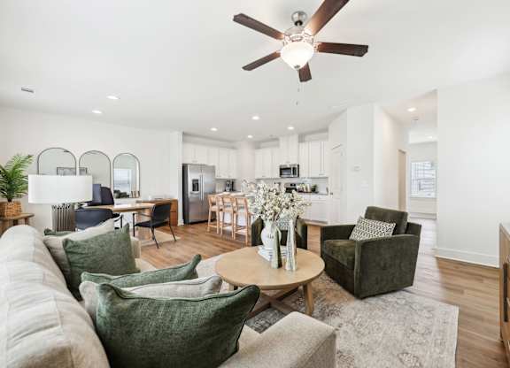 A living room with a white ceiling fan and a grey rug.