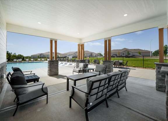 A patio with a table and chairs overlooking a pool.