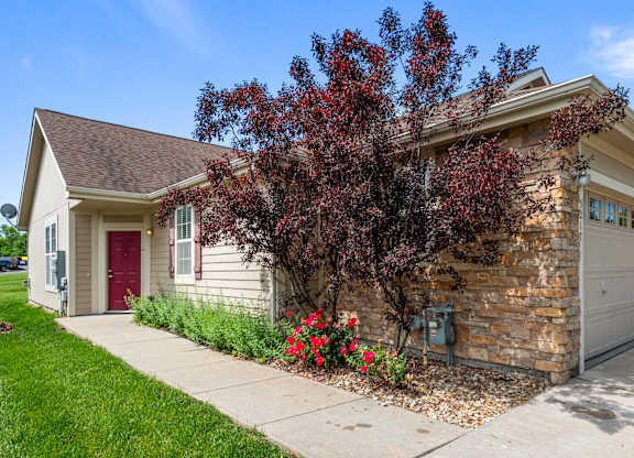 A house with a red door and a tree with red leaves in front.