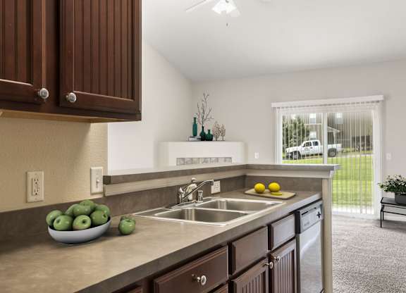 A kitchen with brown cabinets and a bowl of green apples on the counter.