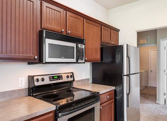 A black refrigerator is in a kitchen with brown cabinets.