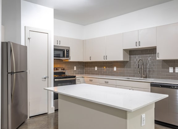 A kitchen with a white counter top and stainless steel appliances.