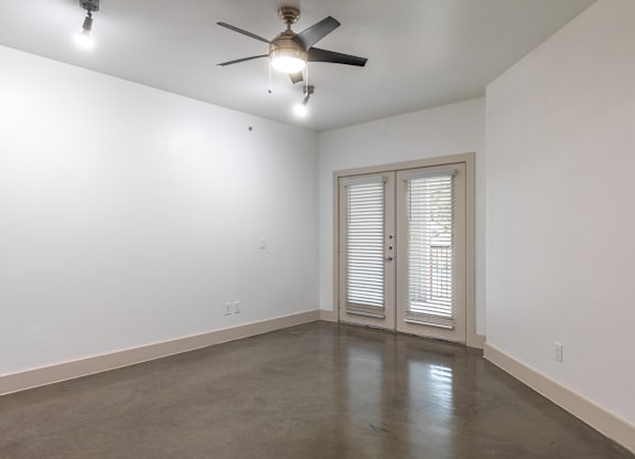 A room with a ceiling fan and sliding glass doors.