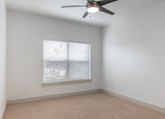 A room with a ceiling fan and a window with blinds.