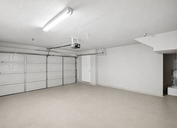 A spacious garage with a closed white door and a white ceiling.
