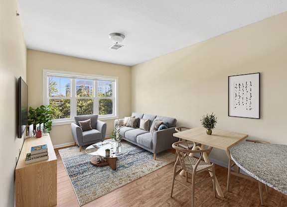 A living room with a grey couch, a coffee table, a small table, and a television.