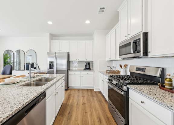 A modern kitchen with white cabinets and stainless steel appliances.