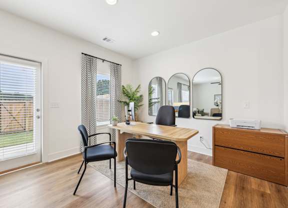 A room with a desk, chairs, and mirrors.