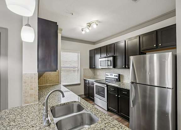A modern kitchen with a stainless steel refrigerator and black cabinets.