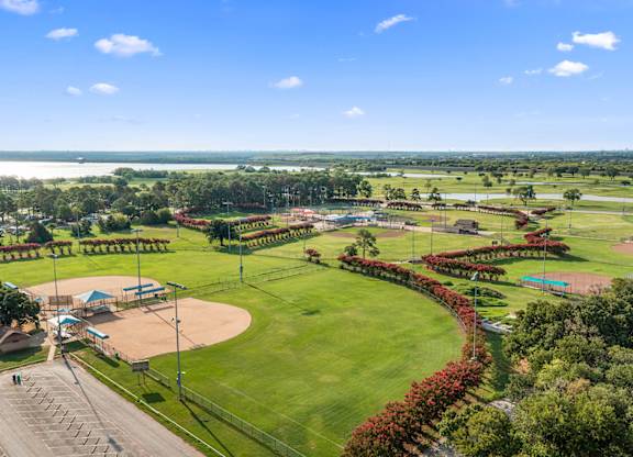 A beautifully maintained park with a baseball field and a tennis court.