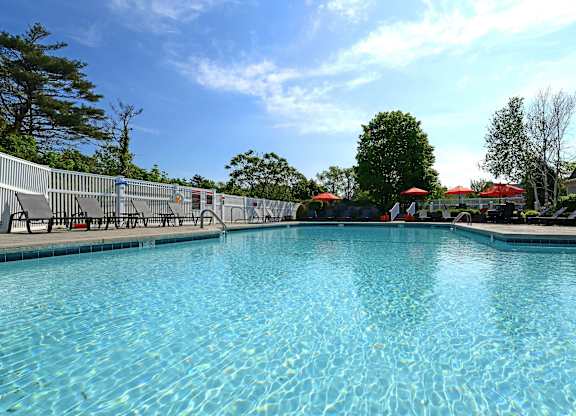 A large swimming pool with a blue tinted water and a white fence around it.