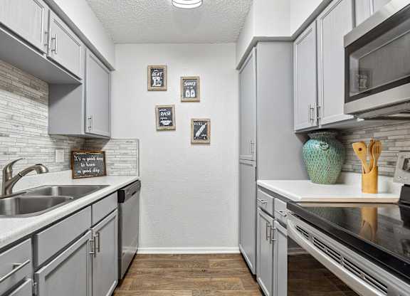 A kitchen with grey cabinets and a white counter top.