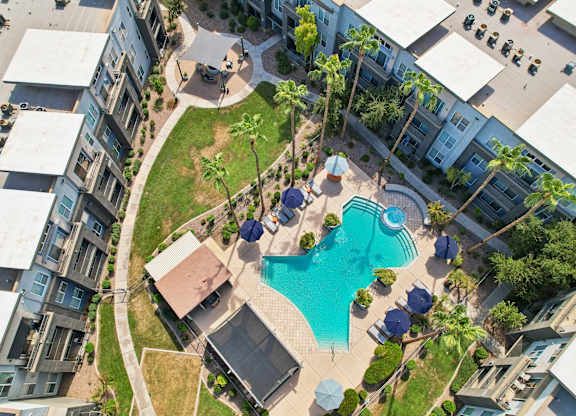 A swimming pool surrounded by a grassy area and a few trees.
