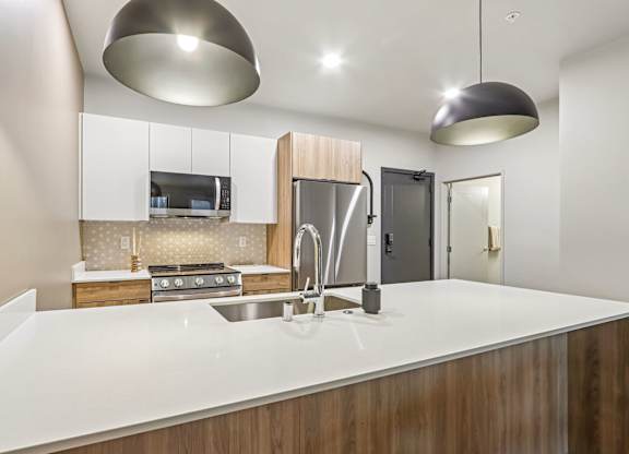 A modern kitchen with a white countertop and wooden cabinets.