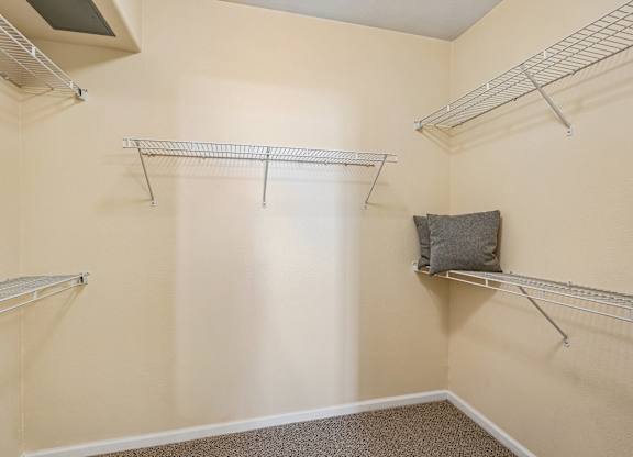 Empty room with three shelves and a pillow on one of them.