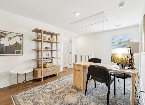A room with a desk, chair, and shelves.