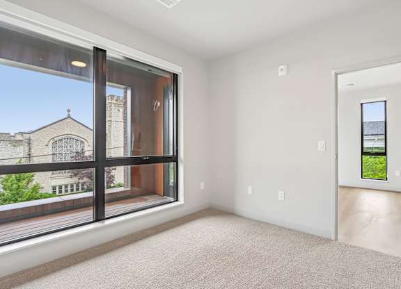 A large empty room with a view of a building outside through the window.